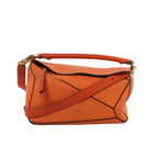 Orange LOEWE Puzzle Medium leather handbag with geometric paneling, top handle, adjustable shoulder strap and gold-tone hardware.