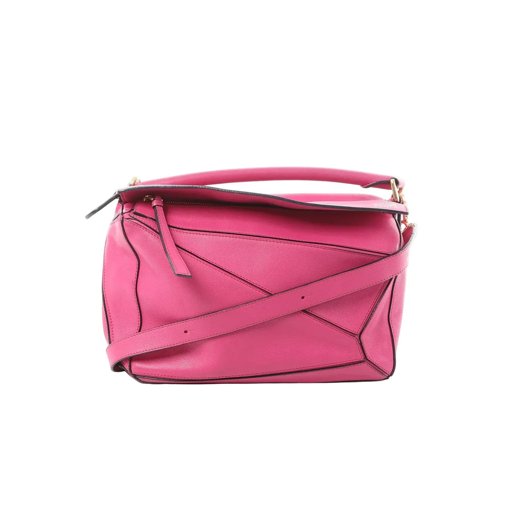 LOEWE Puzzle Medium handbag in bright pink leather with geometric panel construction, top handle, zip-top closure, and detachable shoulder strap on a white background.
