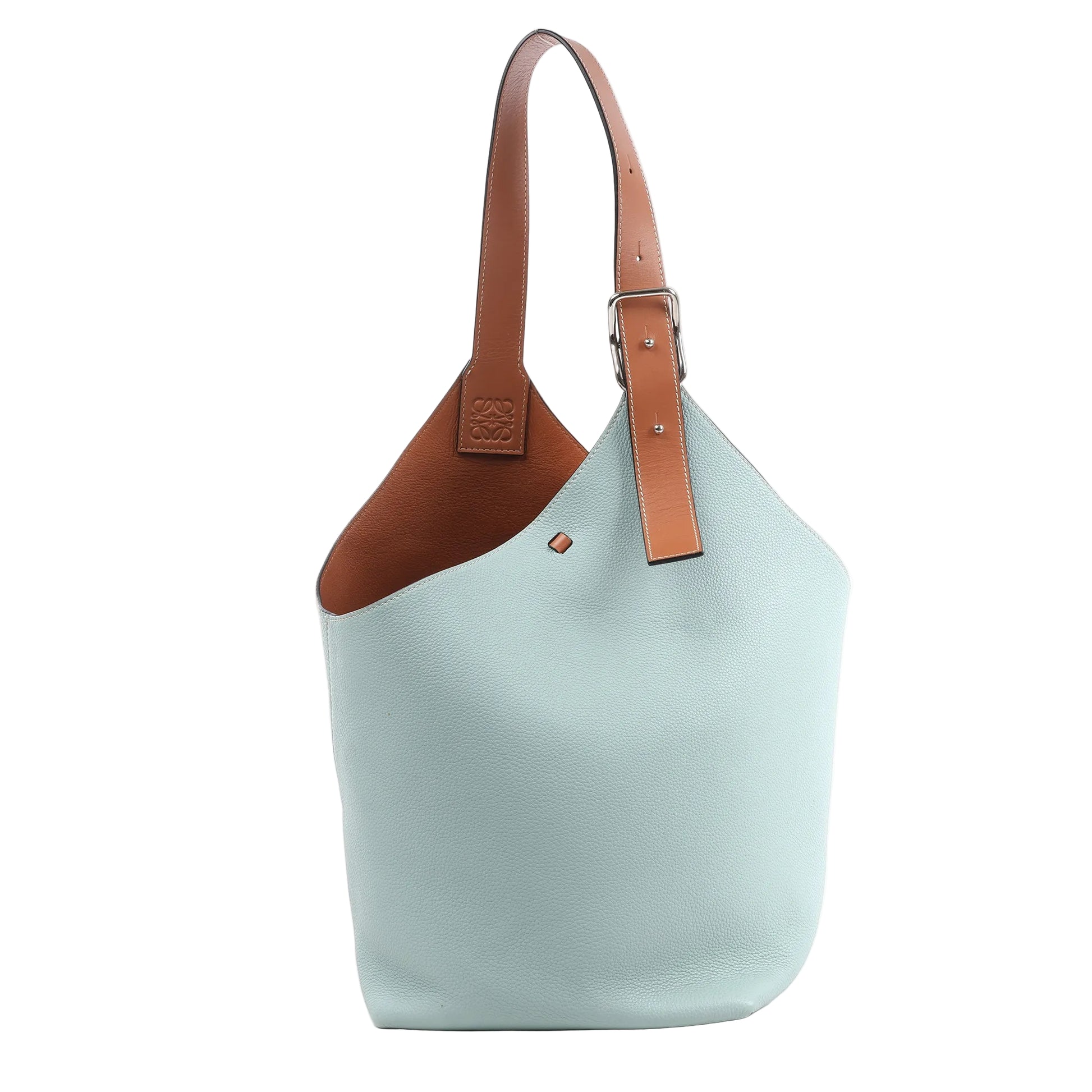 Front view of the LOEWE Balloon Leather Shoulder Bag in light blue and brown, featuring a soft blue pebbled leather body, adjustable brown leather strap with silver-tone buckle, and embossed LOEWE logo near the top, displayed against a white background.