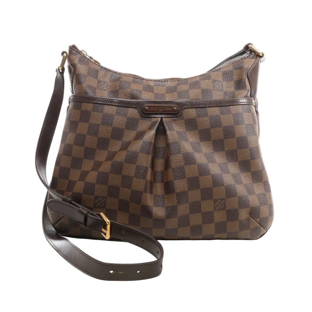 Louis Vuitton Bloomsbury PM crossbody bag in brown Damier Ebene coated canvas with dark leather trim, adjustable shoulder strap, front pleated detail, and gold-tone hardware on a white background.