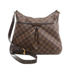 Louis Vuitton Bloomsbury PM crossbody bag in brown Damier Ebene coated canvas with dark leather trim, adjustable shoulder strap, front pleated detail, and gold-tone hardware on a white background.