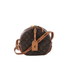 Front view of Louis Vuitton Monogram canvas Boite Chapeau Souple MM round bag with tan leather trim, adjustable shoulder strap, luggage tag and padlock on a white background.