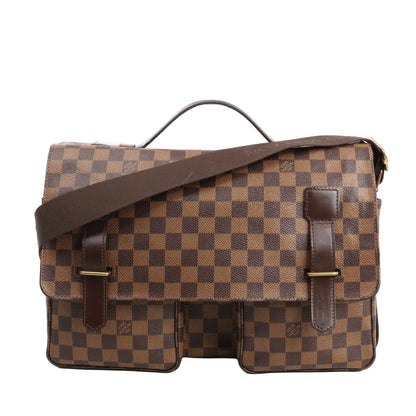 Louis Vuitton Broadway shoulder bag in brown Damier Ebene canvas with dark brown leather trim, top handle, adjustable fabric strap, and dual front pockets.