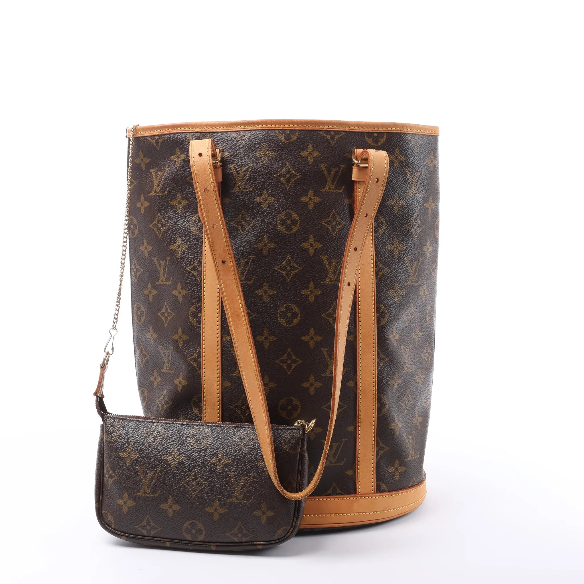 Angled front view of a brown Louis Vuitton Bucket GM Monogram canvas shoulder bag with tan leather trim, long straps and a matching zip pouch.