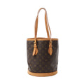 Front view of Louis Vuitton Bucket PM bag in brown Monogram canvas with vachetta leather trim base, adjustable tan leather shoulder straps, and side strap details.