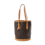 Front view of Louis Vuitton Bucket PM bag in brown Monogram canvas with vachetta leather trim base, adjustable tan leather shoulder straps, and side strap details.