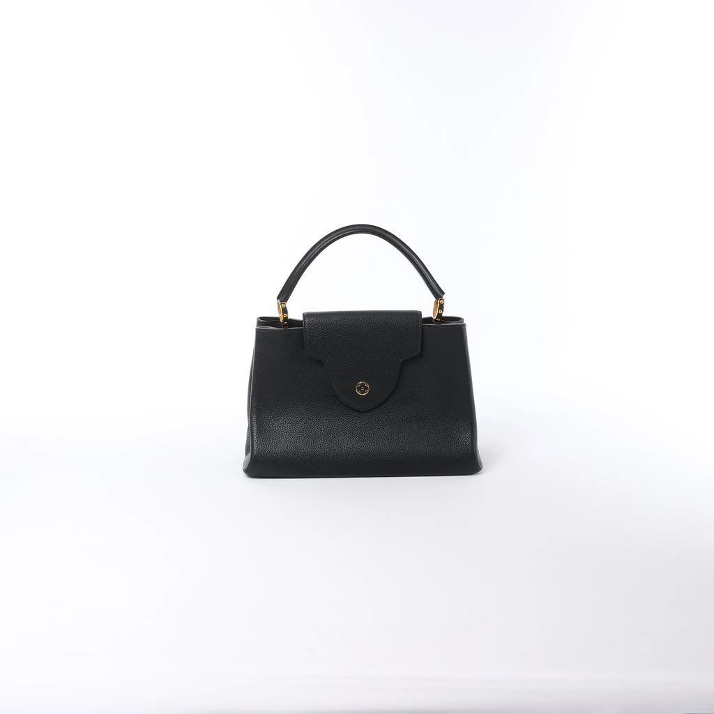 Front view of black Louis Vuitton Capucines MM leather top-handle bag with flap closure and gold-tone hardware on a white background.