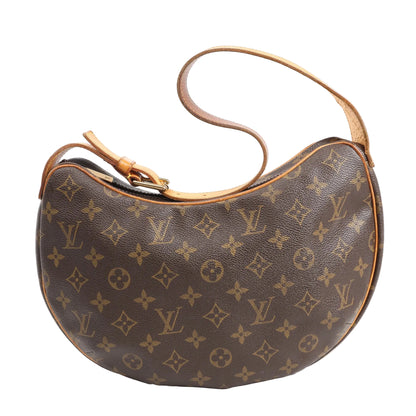 Louis Vuitton Croissant MM Shoulder Bag in brown Monogram canvas with crescent shape, natural cowhide leather strap, and gold-tone hardware on a white background.