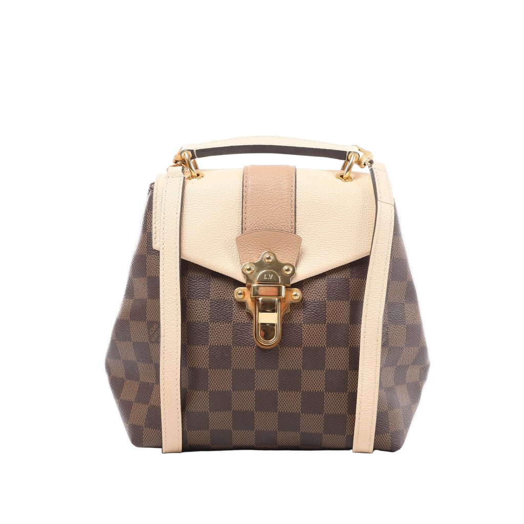 Front view of a Louis Vuitton Clapton backpack with brown checkerboard canvas, a beige leather flap, pale leather straps and a gold-tone clasp.