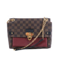 Louis Vuitton Vavin PM bag in brown Damier Ebene canvas with burgundy leather pocket, gold-tone clasp and chain strap.
