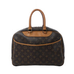 Louis Vuitton Deauville handbag in brown Monogram canvas with tan vachetta leather handles, front slip pocket, zip-top closure, and gold-tone hardware on white background.