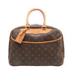 Louis Vuitton Deauville handbag in brown Monogram coated canvas with natural cowhide leather trim, rolled top handles, luggage tag, front slip pocket, and gold-tone hardware on a white background.