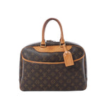 Louis Vuitton Deauville handbag in brown Monogram canvas with tan vachetta leather trim, top handles, and hanging leather luggage tag on a white background.
