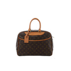 Louis Vuitton Deauville handbag in brown Monogram canvas with tan vachetta leather trim, top handles, and hanging leather luggage tag on a white background.