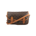 Louis Vuitton Gibecière MM crossbody bag in brown Monogram canvas with tan leather trim, flap front, and long shoulder strap on white background