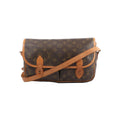 Louis Vuitton Gibecière MM crossbody bag in brown Monogram canvas with tan leather trim, flap front, and long shoulder strap on white background