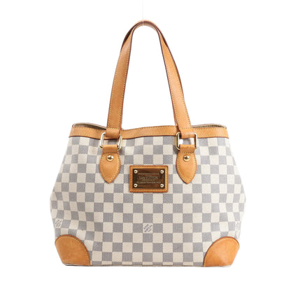 Louis Vuitton Hampstead PM Handbag N51207 in Damier Azur coated canvas with natural vachetta leather trim, dual top handles, gold-tone hardware, and a front logo-engraved nameplate, displayed against a white background.