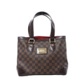Louis Vuitton Hampstead PM shoulder bag in brown Damier Ebene canvas with dark leather handles, gold-tone hardware, front logo plaque, and red interior visible on white background.