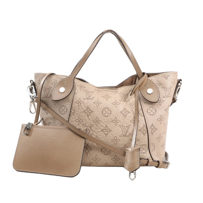 Louis Vuitton Hina Shoulder Bag M54351 in beige perforated Mahina monogram leather with silver-tone hardware, top handles, crossbody strap, and matching removable pouch on a white background.