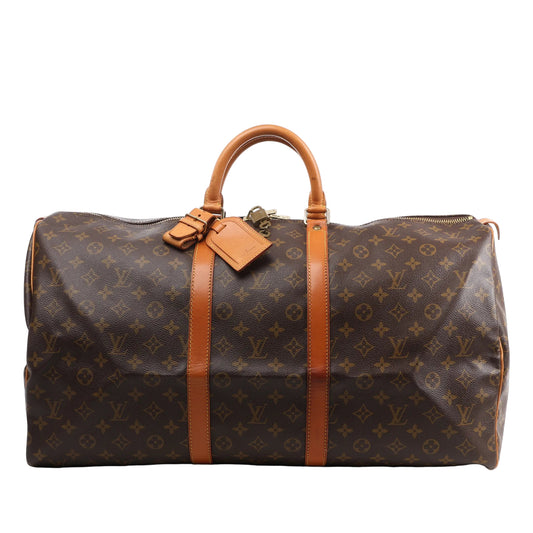 Louis Vuitton Monogram Canvas Keepall 55 Travel Bag M41424 featuring brown LV monogram canvas, tan leather handles and trim, gold-tone hardware, zip closure, and attached leather name tag, displayed on a white background.