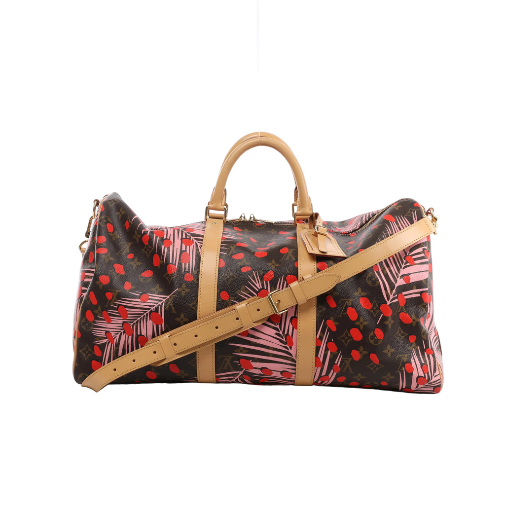Louis Vuitton Keepall Bandoulière 50 with brown Monogram, pink palm leaves, red dots, tan leather handles and shoulder strap, and gold-tone hardware.