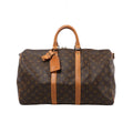 A brown Louis Vuitton Keepall Bandoulière 45 travel bag in Monogram coated canvas, featuring tan leather top handles, central leather trim, and an attached luggage tag.