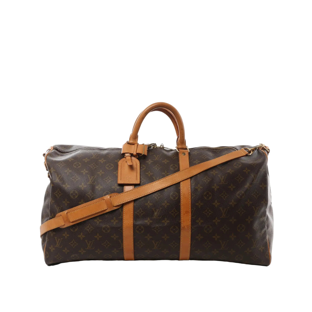 Louis Vuitton Monogram canvas Keepall Bandoulière 55 travel bag with tan leather trim, top handles, detachable shoulder strap, and hanging leather tag on a white background.