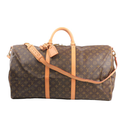 Louis Vuitton Keepall Bandoulière 60 travel bag in Monogram canvas with natural leather trim, featuring dual rolled handles, detachable shoulder strap, luggage tag, and gold-tone hardware, shown against a white background.