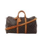Louis Vuitton Keepall Bandoulière 50 brown Monogram canvas duffle bag with vachetta leather handles, trim, luggage tag, and detachable shoulder strap on white background.