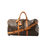 Louis Vuitton Monogram canvas Keepall Bandoulière 50 travel bag in brown with tan leather handles, shoulder strap, luggage tag, padlock, and top zip closure
