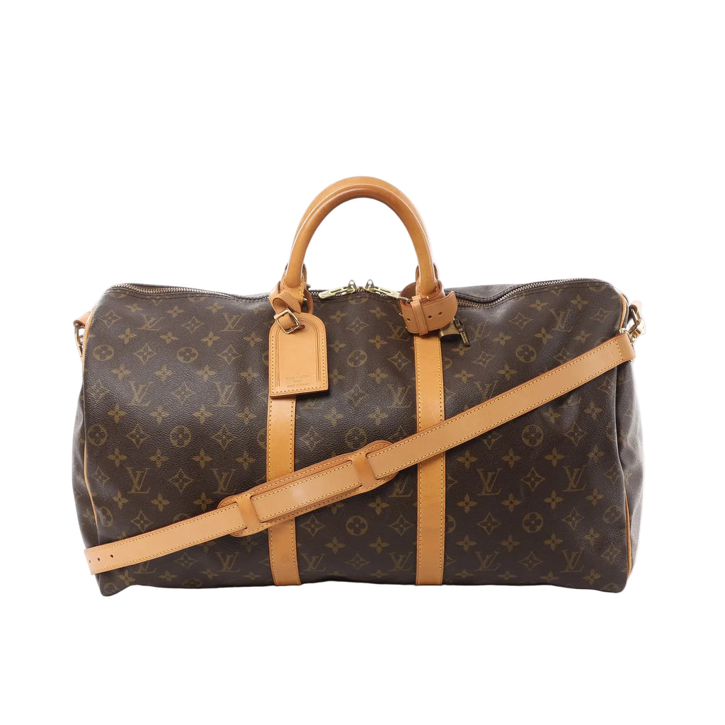 Louis Vuitton Keepall Bandoulière 50 brown Monogram canvas duffle bag with vachetta leather handles, trim, luggage tag, and detachable shoulder strap on white background.