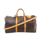 Louis Vuitton Monogram canvas Keepall Bandoulière 50 travel bag with tan leather trim, top handles, detachable shoulder strap, and hanging leather tag on a white background.