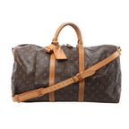 Front view of Louis Vuitton Monogram canvas Keepall Bandoulière 50 with tan leather trim, top handles, luggage tag and adjustable shoulder strap on a white background.