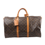 Brown Louis Vuitton Keepall Bandoulière 50 Monogram canvas travel bag with tan leather handles, vertical trim, luggage tag and gold-tone zip hardware.