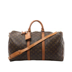 Louis Vuitton Keepall Bandoulière 50 duffle bag in brown Monogram canvas with tan leather handles, luggage tag, and shoulder strap on white background