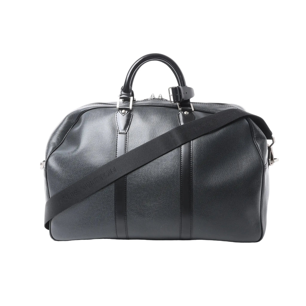 Louis Vuitton Kendall PM black Taiga leather travel bag with top handles, zip closure, silver-tone hardware, and Louis Vuitton branded shoulder strap on white background