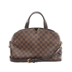 Louis Vuitton Kensington Bowling handbag in brown Damier Ebene coated canvas with dark leather top handles, gold-tone V detail, removable shoulder strap, and structured silhouette on a white background.