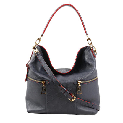 Louis Vuitton Monogram Empreinte Mélie bag in navy blue embossed leather, featuring red trim, dual front zip pockets, gold hardware, and adjustable shoulder strap, model M44012.