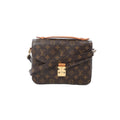 Front view of Louis Vuitton Monogram canvas Pochette Métis MM with tan leather top handle, gold-tone S-lock clasp, and crossbody strap on white background.