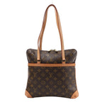 Louis Vuitton Monogram Coussin GM Shoulder Bag in brown coated canvas with natural leather trim, dual flat shoulder straps, and gold-tone zipper, displayed on a white background.