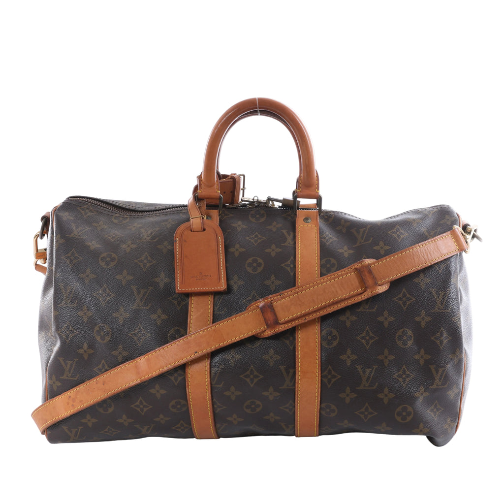 Louis Vuitton brown Monogram canvas travel bag with tan leather handles and trim, adjustable shoulder strap, top zipper and leather luggage tag.