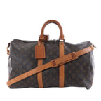 Louis Vuitton brown Monogram canvas travel bag with tan leather handles and trim, adjustable shoulder strap, top zipper and leather luggage tag.