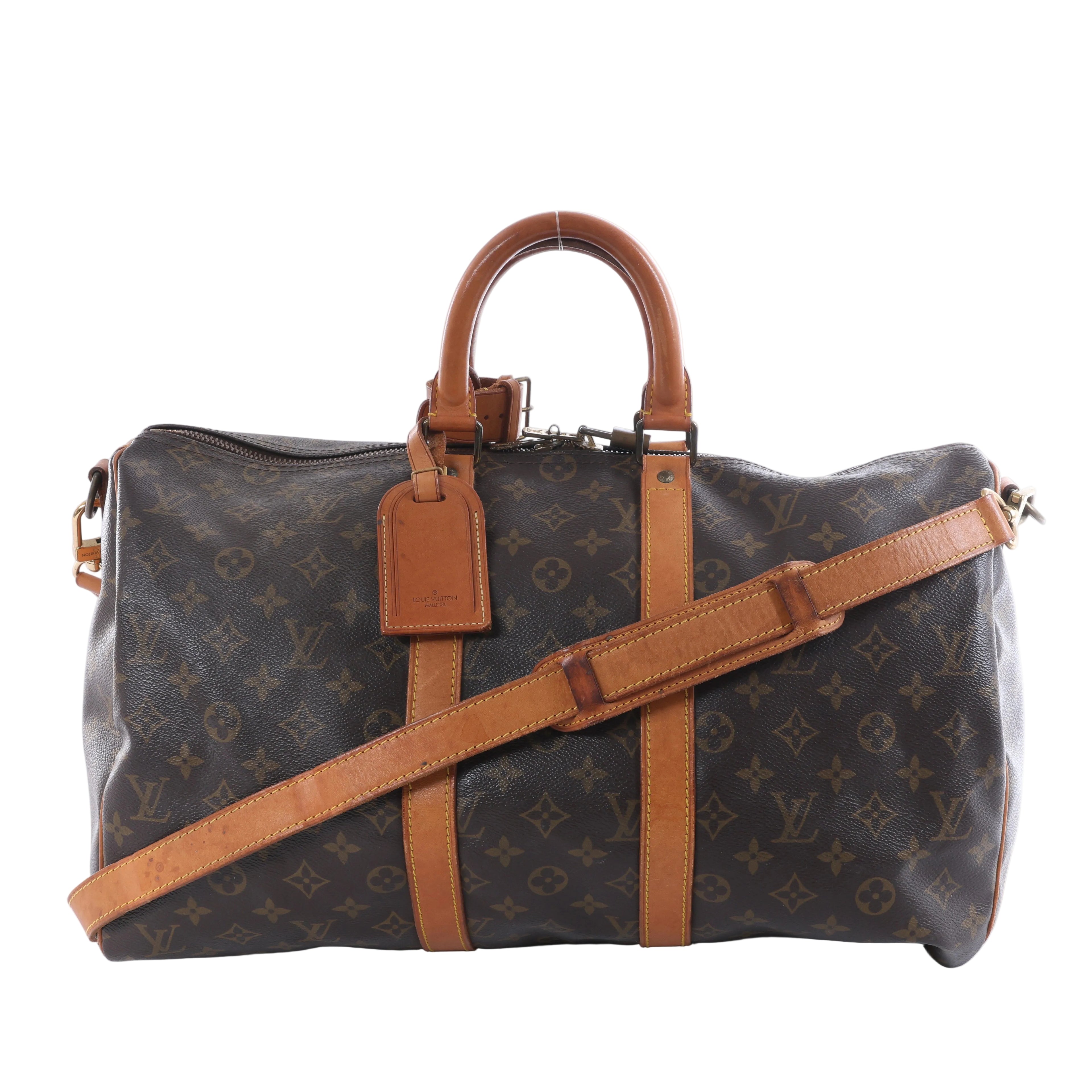 Louis Vuitton brown Monogram canvas travel bag with tan leather handles and trim, adjustable shoulder strap, top zipper and leather luggage tag.