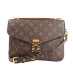 Louis Vuitton Monogram Pochette Metis handbag in brown coated canvas with all-over LV monogram, gold-tone S-lock closure, adjustable leather strap, and top handle, shown against a white background.