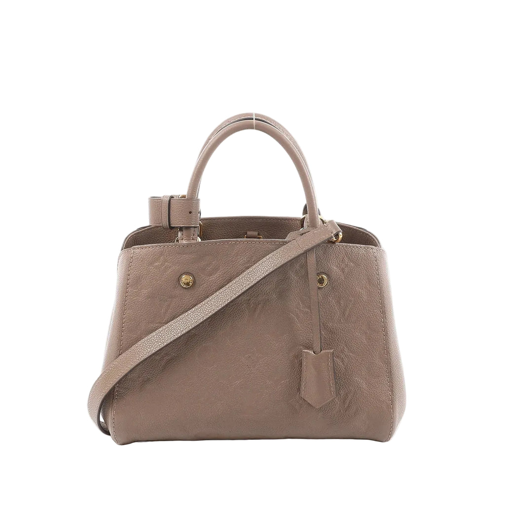Louis Vuitton Montaigne BB handbag in taupe-brown Monogram Empreinte leather with top handle, detachable shoulder strap, and hanging leather tag on a white background.