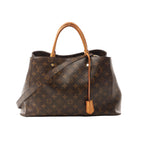 Louis Vuitton Montaigne GM handbag in brown Monogram canvas with vachetta leather top handles, leather hang tag, and detachable shoulder strap on white background.