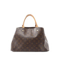 Louis Vuitton Montaigne MM handbag in brown Monogram canvas with natural cowhide leather top handles, structured silhouette, and gold-tone hardware on a light gray background.