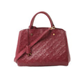 Burgundy Louis Vuitton Montaigne MM Monogram Empreinte leather handbag with top handles, detachable shoulder strap, and gold-tone hardware on a white background.