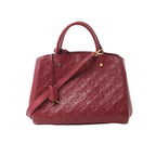 Burgundy Louis Vuitton Montaigne MM Monogram Empreinte leather handbag with top handles, detachable shoulder strap, and gold-tone hardware on a white background.