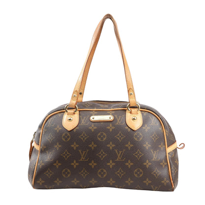 Louis Vuitton Montorgueil PM M95565 shoulder bag in brown Monogram coated canvas with natural leather trim, dual flat shoulder straps, gold-tone hardware, and LV nameplate on the front.